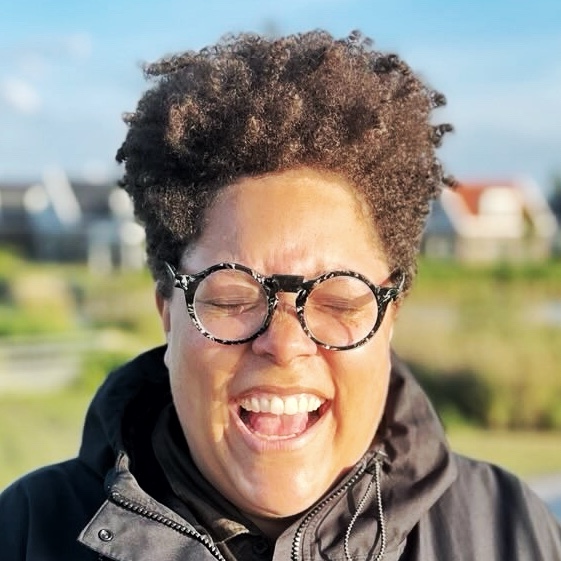 A person laughing with their eyes closed, Dutch landscape in the background