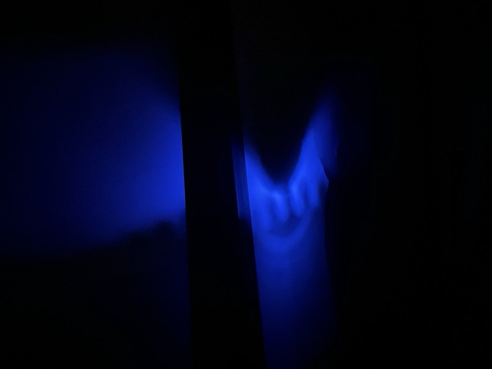 A dim blue light hits a bedroom wall at nighttime