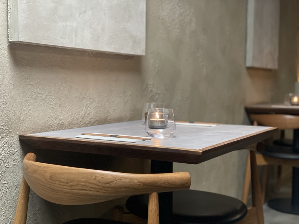 A two-person gray table with wood finish at a ramen restaurant waits for guests