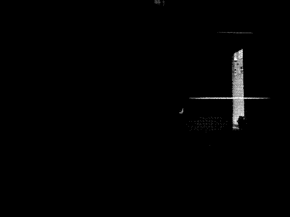 A woman sits in a dark room with her back to the camera, readying herself to get up
